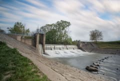 Seuil sur une rivière bordée d’arbres, l’eau passe en lame